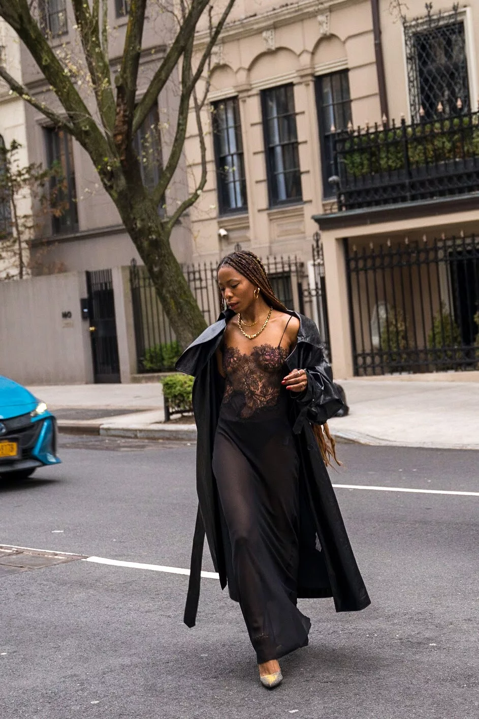 she is wearing a black lace slip dress, black faux leather trench coat, red mini bag and gunmetal pumps