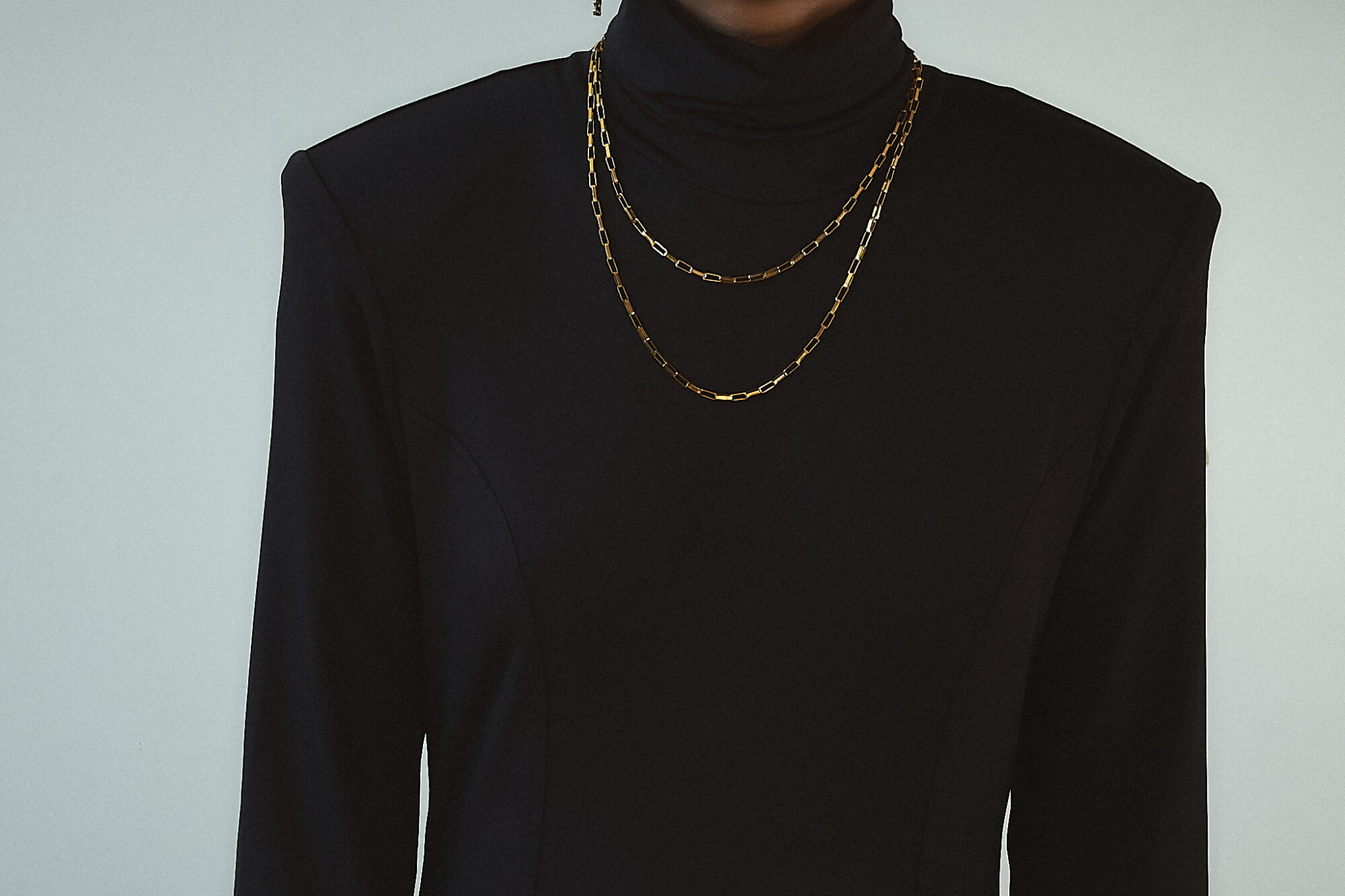 Close-up of the front of a black backless maxi dress, showcasing its high neckline and long sleeves, exuding sophistication and timeless style.