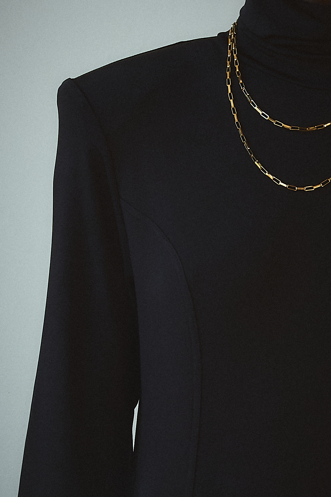 Close-up of the front of a black backless maxi dress, showcasing its high neckline and long sleeves, exuding sophistication and timeless style.