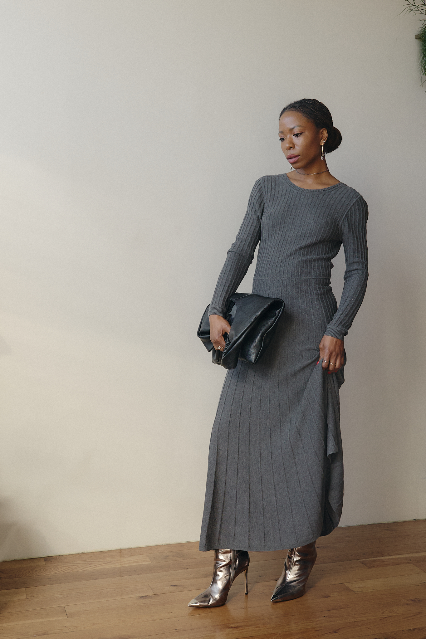 Chic fall outfit featuring a grey ribbed knit long-sleeve dress, silver stiletto boots, and a black oversized clutch — modern minimalist fashion for colder seasons.