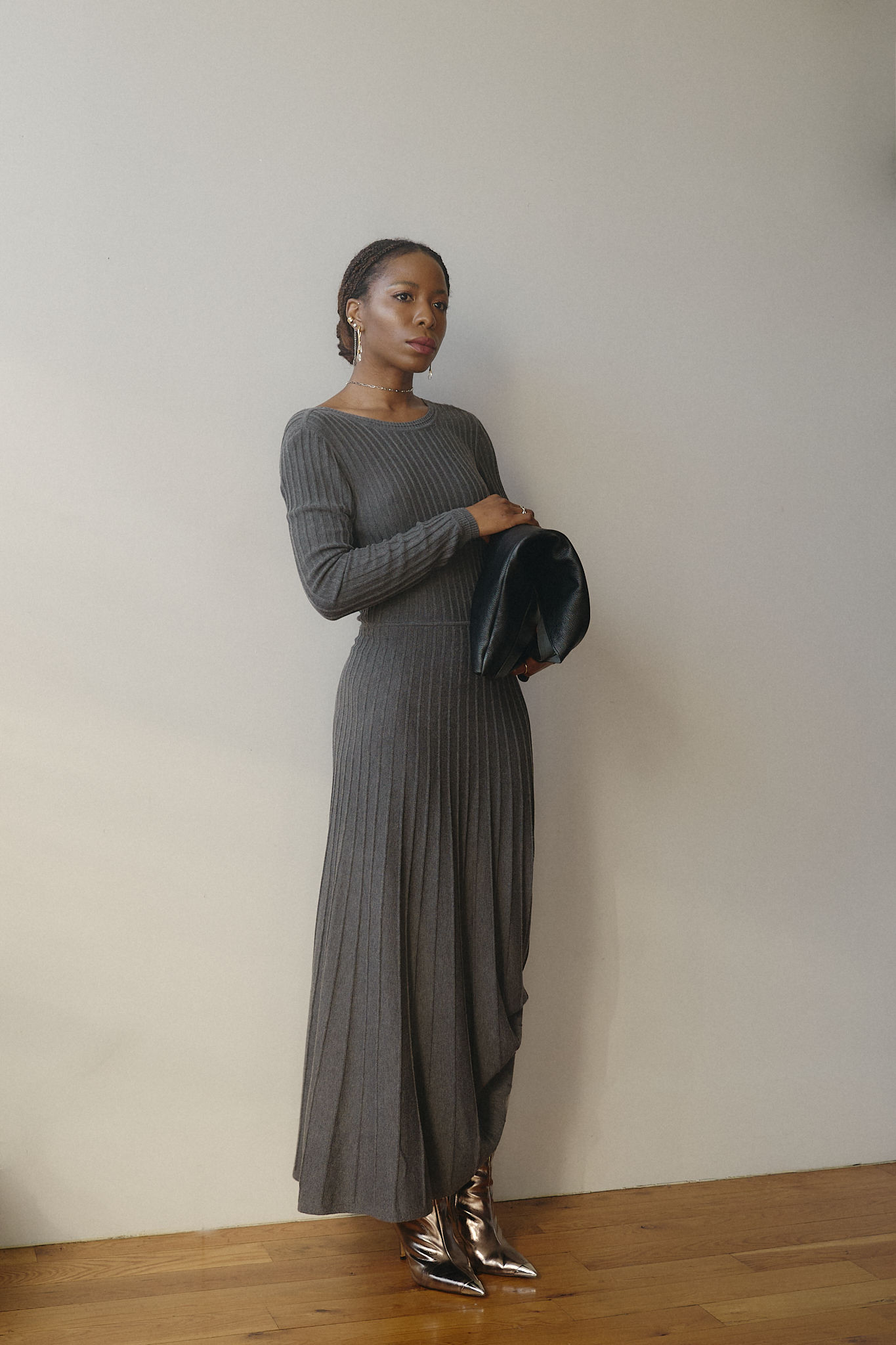 Chic fall outfit featuring a grey ribbed knit long-sleeve dress, silver stiletto boots, and a black oversized clutch — modern minimalist fashion for colder seasons.