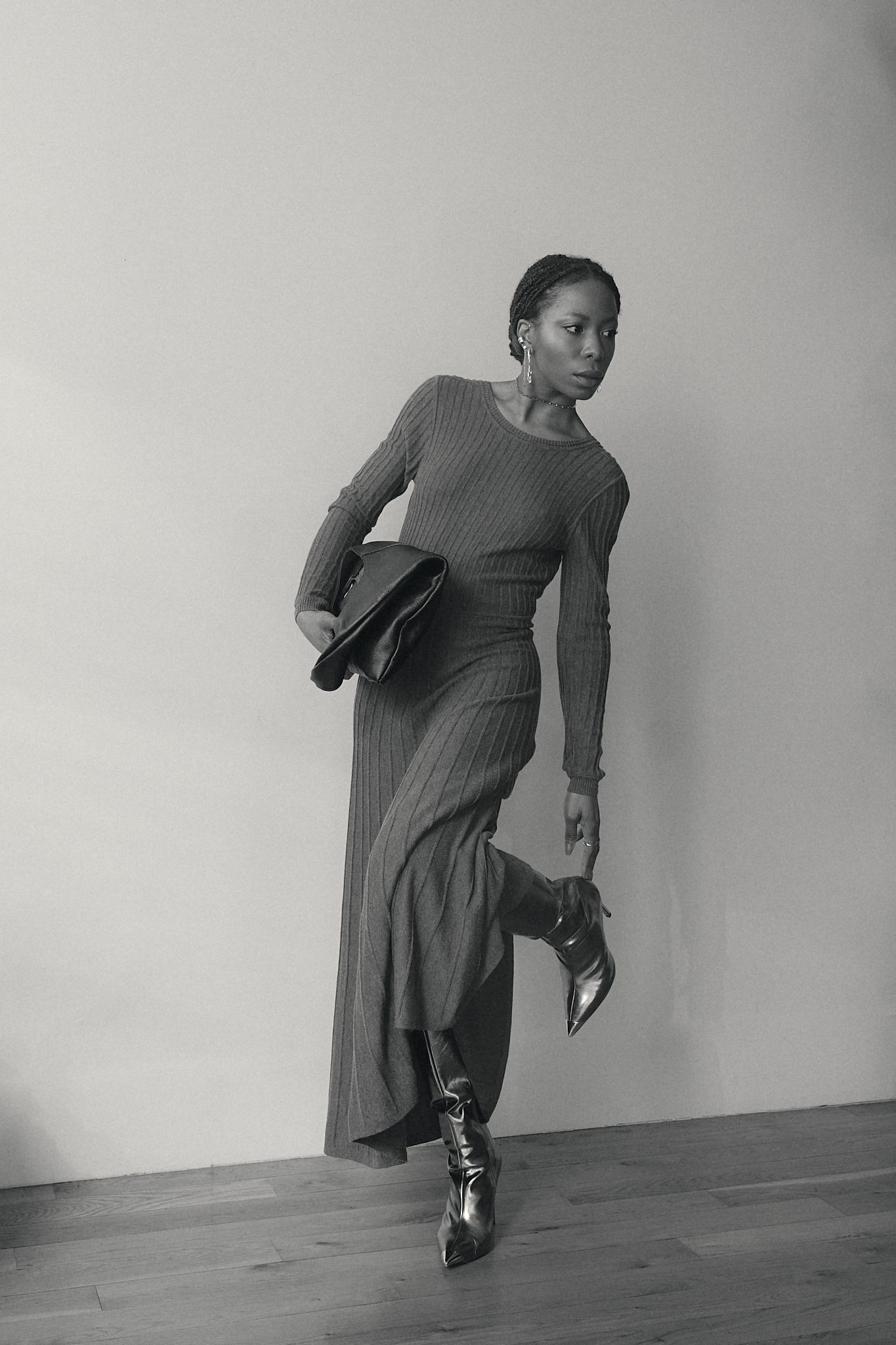 Chic fall outfit featuring a grey ribbed knit long-sleeve dress, silver stiletto boots, and a black oversized clutch — modern minimalist fashion for colder seasons.