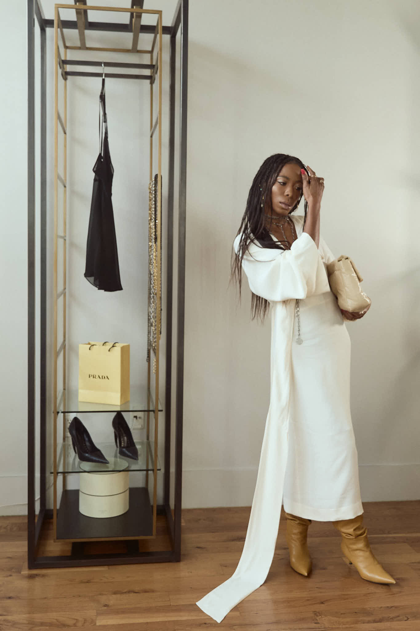 Full body shot of a woman in a white maxi dress, tan slouchy boots, and layered silver jewelry.